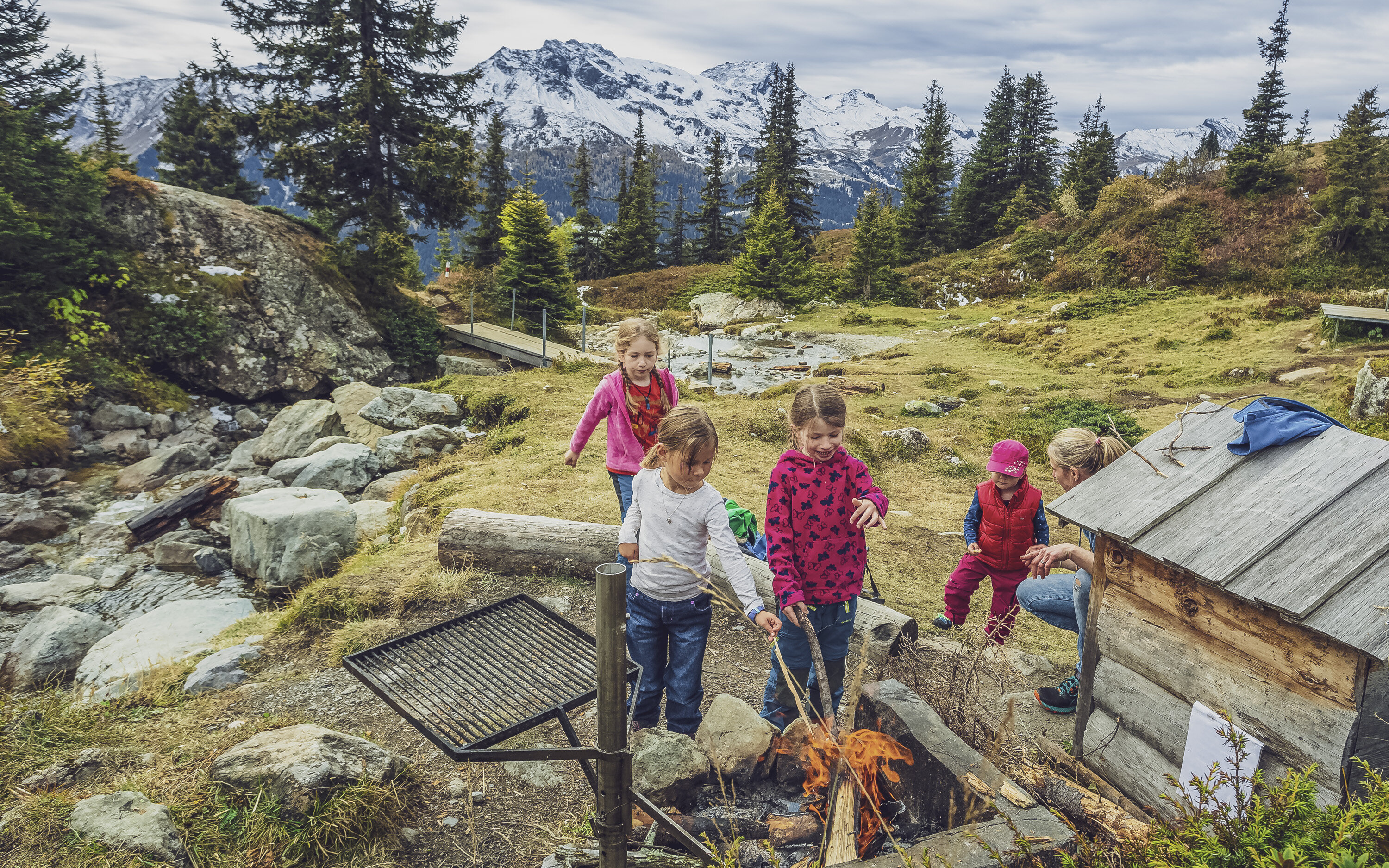 Mehrere Kinder am Würste braten über der Feuerstelle  | © Davos Klosters Moutains 