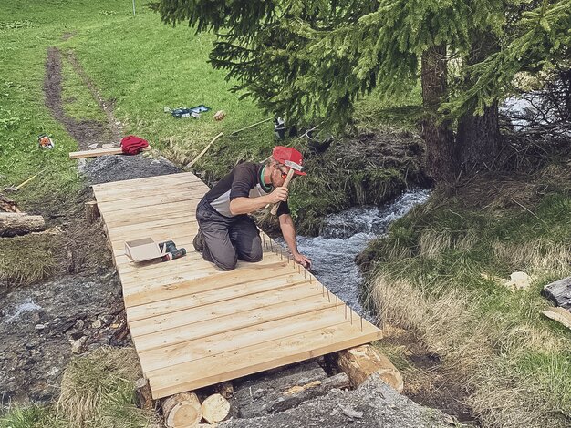 Die Trail Crew baut eine neue Holzbrücke, damit der Bach von Fussgängern und Bikern überquert werden kann. | © Davos Klosters Mountains