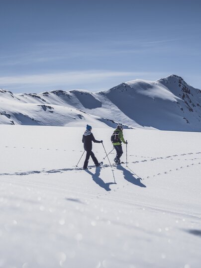 Two women walk through the deep snow on snowshoes. | © Davos Klosters Mountains