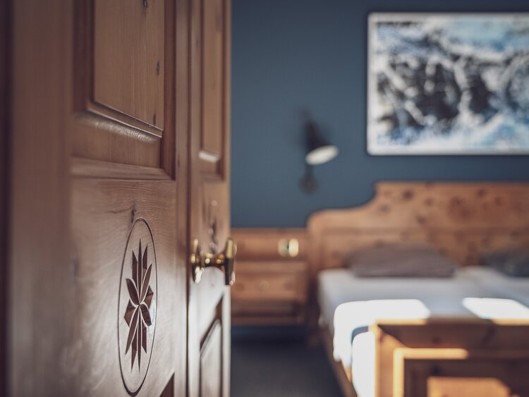 Zimmer mit Doppelbett, Bettwäsche und Nachttischlampe | © Davos Klosters Mountains 